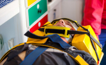 Injured man in a stretcher and an emergency worker inside an ambulance at a scene of a train accident simulation